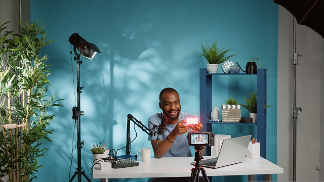 A man demonstrating a product to a camera in a well-lit home studio.