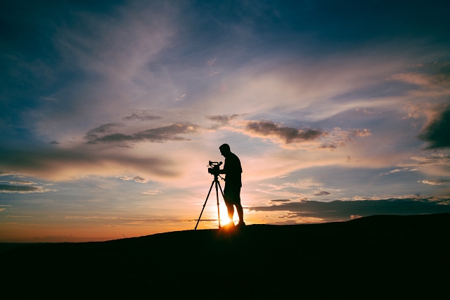 Silhouette of a photographer capturing the sunset on a hill- video marketing