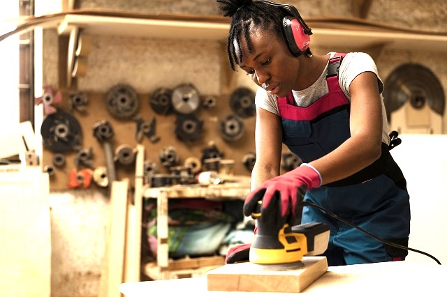 A lady in a woodworking workshop, illustrating the concept of self-employment and career building in the crafts industry.